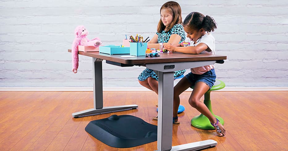 Two children sitting on Kids Active Stools by UPLIFT Desk and playing at a height adjustable desk